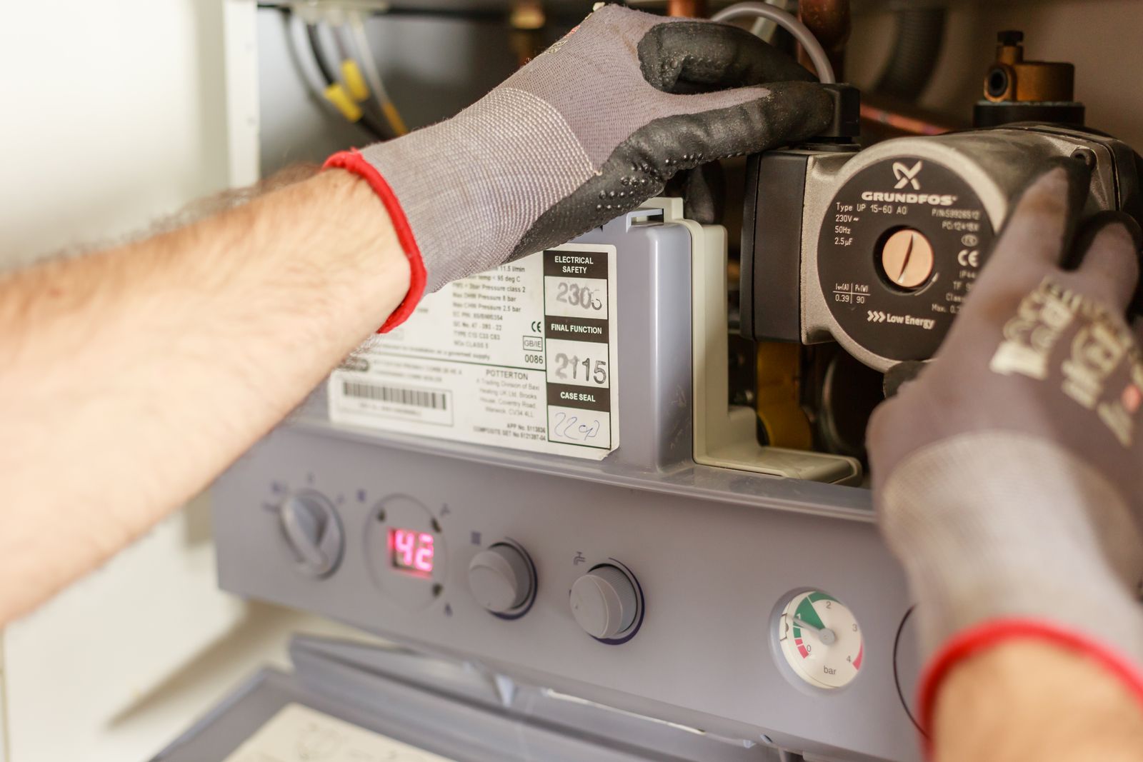 Gloved technician adjusting the control panel of a home heating system